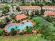Aerial view of community pool with lounge chairs, a tennis court, and nearby townhomes at 4730 Coral Castle Dr, Kissimmee, FL 34746