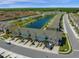 Wide aerial view of the townhome community with a lake, pool, green space, and surrounding trees at 4732 Coral Castle Dr, Kissimmee, FL 34746