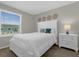 Bedroom with a white bed frame, two decorative pillows, side table, lamp, and a window for natural light at 4732 Coral Castle Dr, Kissimmee, FL 34746