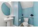 Powder room with a pedestal sink, round mirror, and light blue walls at 8896 Reymont St, Orlando, FL 32827