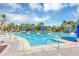 Beautiful community pool with comfortable blue lounge chairs, palm trees, lush landscaping and sunny blue skies with picturesque clouds at 8896 Reymont St, Orlando, FL 32827