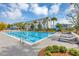 Resort-style community pool with blue skies, comfortable loungers, palm trees, and a modern condominium building in the background at 8896 Reymont St, Orlando, FL 32827