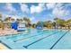 Stunning community pool featuring lap lanes, comfortable lounge chairs, lush landscaping, and sunny blue skies with picturesque clouds at 8896 Reymont St, Orlando, FL 32827