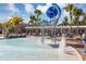 Charming community splashpad featuring an overhead water feature, lounge seating, lush landscaping, palm trees, and a modern clubhouse at 8896 Reymont St, Orlando, FL 32827