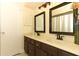 Bathroom features a double vanity with tan countertop, dark wood cabinets and wall mirrors at 1157 Duncan Dr, Winter Springs, FL 32708
