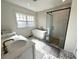 Modern bathroom with dual sinks, a soaking tub, a glass-enclosed shower, and decorative tile floor at 138 W Stetson Ave, Deland, FL 32720