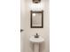 Modern powder room with pedestal sink, stylish lighting, and a decorative mirror at 1457 Resolute St, Celebration, FL 34747