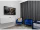 Bedroom with mounted TV, seating area with blue chairs, a white cabinet, and dark, sleek curtains at 2352 Zaballina Pl, Kissimmee, FL 34747