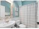 Stylish bathroom with a modern sink, decorative mirror, and a shower with a striped curtain at 3469 Foxton Ct, Oviedo, FL 32765