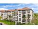 Beautiful condo building with a red tile roof and multiple balconies surrounded by green landscaping and palm trees at 4114 Breakview Dr # 11002, Orlando, FL 32819