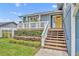 Inviting front porch with charming details, decorative railing, beautiful flowers and a striking yellow door at 417 Barclay Ave, Altamonte Springs, FL 32701