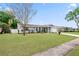 Well-maintained single-story home features a lush green lawn and mature trees, enhancing its curb appeal at 4729 Arrow Rd, Orlando, FL 32812