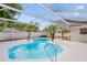 Enclosed pool area showcases a uniquely shaped pool, palm trees, and a surrounding patio for relaxation at 4729 Arrow Rd, Orlando, FL 32812