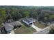 An aerial view of a white single-story home with a dark roof and driveway surrounded by a lush green forest at 54 Malauka Trak, Ocklawaha, FL 32179