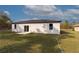 A view of the home's white rear facade, with sliding glass door, backyard and lawn at 54 Malauka Trak, Ocklawaha, FL 32179