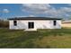 The backyard of the property features a sliding glass door that leads to the patio, with a simple modern facade at 54 Malauka Trak, Ocklawaha, FL 32179