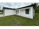 The house is white with black trim and green grass with a sidewalk leading to the front door at 54 Malauka Trak, Ocklawaha, FL 32179