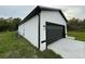 A modern home's garage with a black door and white exterior against a cloudy sky at 54 Malauka Trak, Ocklawaha, FL 32179