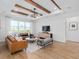 Bright living room with wood beam ceiling, modern lighting, and tan leather sofa at 5517 Flame Vine Way, St Cloud, FL 34771