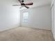 A neutral bedroom features a ceiling fan, bright window, neutral walls and plush carpeting at 563 Copperdale Ave, Winter Garden, FL 34787