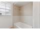 Bathroom showcasing a white tiled tub and a frosted glass window for privacy at 7602 Glenmoor Ln, Winter Park, FL 32792