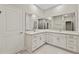 Bright bathroom with double vanity, white cabinetry, and large mirrors reflecting the shower and toilet area at 1755 Waterview Dr, Leesburg, FL 34748