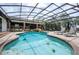 Stunning screened pool area with rock waterfall, outdoor kitchen, and lounge seating at 4469 Old Bear Run, Winter Park, FL 32792