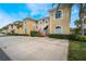 Charming condo building featuring two stories, yellow siding, white railings, and lush green landscaping with palm trees at 5201 Lake Marion Golf Resort # 5201, Kissimmee, FL 34759