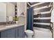 Modern bathroom featuring a gray vanity, neutral stone countertop, and patterned shower with a blue curtain at 1224 Union Club Dr, Winter Garden, FL 34787