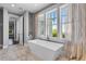 Luxurious bathroom featuring a standalone tub, large windows with sheer curtains, and marble floors at 1224 Union Club Dr, Winter Garden, FL 34787