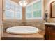 Luxurious soaking tub next to sunlit windows and stone tiling providing a serene and spa-like experience at 12706 S Lake Sawyer Ln, Windermere, FL 34786