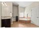 Bright bathroom with a soaking tub, granite vanity, and neutral tile at 10820 Wyandotte Dr, Clermont, FL 34711