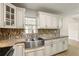 Bright kitchen boasts white cabinets, granite counters, stainless steel sink, and modern mosaic tile backsplash at 1109 Beatrice Dr, Orlando, FL 32810