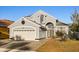 Home exterior with arched entryway, two-car garage, landscaped front yard, and gray paint at 12557 Crayford Ave, Orlando, FL 32837