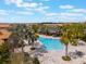 Aerial view of pool with palm trees and patio seating nestled within lush community landscaping at 1312 Shinnecock Hills Dr, Davenport, FL 33896