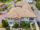Aerial view of two-story home with tile roof, balcony, stone accents, and lush landscaping at 1312 Shinnecock Hills Dr, Davenport, FL 33896