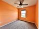 Comfortable bedroom with an orange accent wall, ceiling fan, neutral carpet, and a window that provides natural light at 14533 Orchid Island Dr, Orlando, FL 32827
