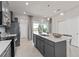 Modern kitchen features an island with sink, pendant lighting, stainless steel appliances, and slider doors to the patio at 16147 Coastal Cove Ln, Clermont, FL 34714