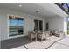 Covered patio with stylish outdoor furniture, overlooking a screened pool and backyard at 16147 Coastal Cove Ln, Clermont, FL 34714