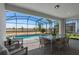 Covered patio features a dining set and comfortable seating overlooking a screened pool and lush backyard at 16147 Coastal Cove Ln, Clermont, FL 34714