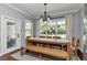 Bright dining room features a large table, bench seating, modern light fixture and large windows overlooking the lush yard at 1819 Sw 29Th St, Ocala, FL 34471
