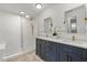 Bright bathroom featuring a double vanity with blue cabinets, white countertops and brass fixtures at 201 Cedarwood Dr, Maitland, FL 32751