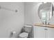 Bright bathroom with a round mirror, toilet, and vanity with granite countertops offers a functional space at 2081 The Oaks Blvd, Kissimmee, FL 34746