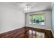 Bright bedroom with hardwood floors, fan, and a window overlooking the yard at 2081 The Oaks Blvd, Kissimmee, FL 34746