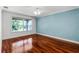 Light-filled bedroom with hardwood floors, ceiling fan, and large window overlooking the yard at 2081 The Oaks Blvd, Kissimmee, FL 34746