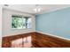 Bright bedroom with hardwood floors, a ceiling fan, neutral walls, and a large window overlooking the landscaped yard at 2081 The Oaks Blvd, Kissimmee, FL 34746