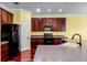 Well-equipped kitchen featuring dark wood cabinets, black appliances, and hardwood flooring at 2081 The Oaks Blvd, Kissimmee, FL 34746