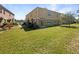 View of backyard showing green grass and the tan two-story home with sliding glass doors at 2124 Betsy Ross Ln, St Cloud, FL 34769