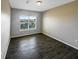 Bright bedroom with dark wood-look floors and a window with neighborhood views at 2124 Betsy Ross Ln, St Cloud, FL 34769
