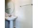 Powder room featuring a pedestal sink, round mirror, and modern fixtures at 2412 Tanger Dr, Kissimmee, FL 34747